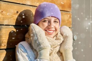 Winter portrait of young woman looking at camera with snowflakes on face
